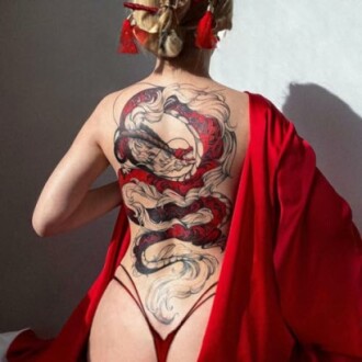 Woman with large dragon tattoo on back wearing red robe.